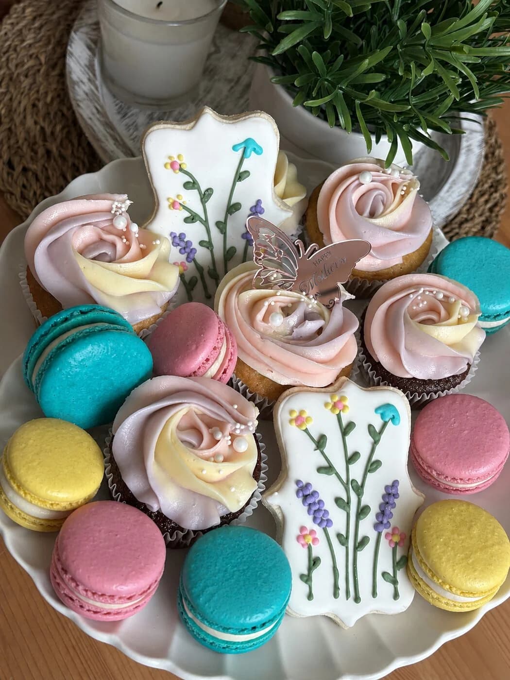 Pastel French macarons in turquoise, pink, and yellow with rose-frosted cupcakes and floral plaque cookies